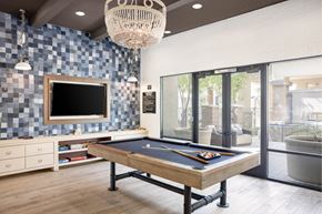 Gilbert apartment for rent - A pool table is in the middle of a room with a tv and a chandelier.
