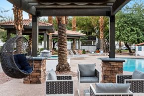 Mesa apartment for rent - A patio with a hanging chair and a pool in the background.