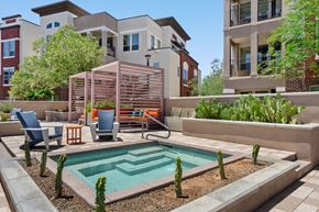 Gilbert apartment for rent - A pool surrounded by a patio with chairs and a table.