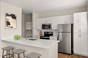 Peoria apartment for rent - A modern kitchen with white cabinets and stainless steel appliances.