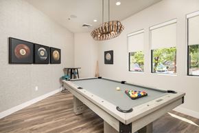 Peoria apartment for rent - A pool table with a green cloth and white balls is in the center of the room.