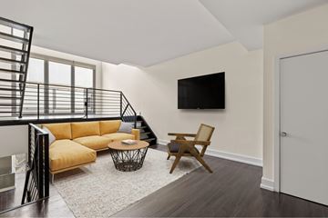 Los Angeles apartment for rent - A living room with a yellow sofa and a black metal staircase.