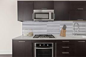 Los Angeles apartment for rent - A modern kitchen with dark brown cabinets and a stove top oven.
