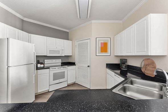 Jacksonville apartment for rent - A kitchen with white cabinets and a black countertop.