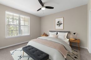 Charlotte apartment for rent - A bedroom with a large bed, a ceiling fan, and a window with blinds.