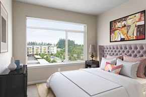 Hillsboro apartment for rent - A bedroom with a large bed and a view of a residential area outside the window.