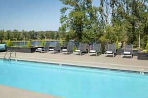 Oregon City apartment for rent - A pool with chairs around it and trees in the background.