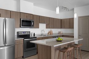 Oregon City apartment for rent - A modern kitchen with a stainless steel refrigerator, microwave, oven, and a marble countertop.