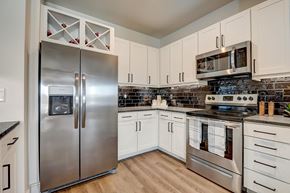 Haslet apartment for rent - A kitchen with a stainless steel refrigerator and oven, and white cabinets.