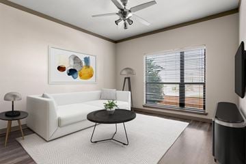 San Antonio apartment for rent - A living room with a white sofa, a small table, a television, and a painting on the wall.