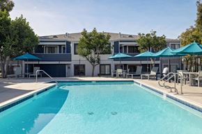 Spring Valley apartment for rent - A swimming pool with a blue umbrella and a building in the background.