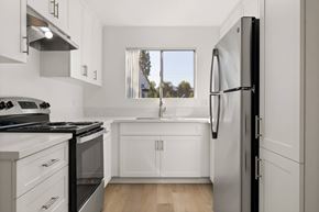 El Cajon apartment for rent - A modern kitchen with white cabinets and a black refrigerator.