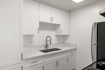 National City apartment for rent - A kitchen with white cabinets and a black refrigerator.