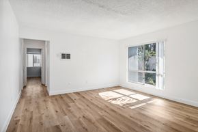 El Cajon apartment for rent - A room with wooden floors and a window showing trees outside.