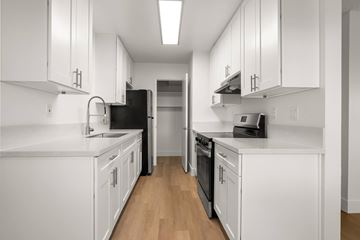 El Cajon apartment for rent - A kitchen with white cabinets and black appliances.