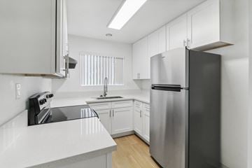 El Cajon apartment for rent - A modern kitchen with a stainless steel refrigerator and white cabinets.