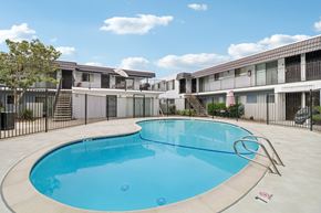 El Cajon apartment for rent - A swimming pool in front of a building with a black fence around it.