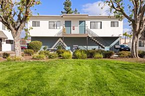 El Cajon apartment for rent - A white two-story house with a green lawn in front.