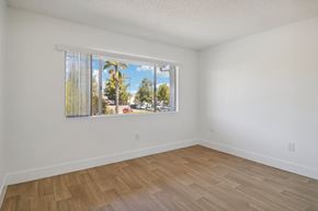 Ramona apartment for rent - A room with a window showing a view of trees and a street.