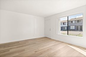 El Cajon apartment for rent - Empty room with wooden flooring and a window showing a building outside.