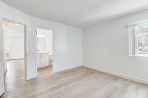 Lakeside apartment for rent - A room with white walls and wooden flooring, with a window showing a building outside.