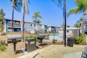 Lakeside apartment for rent - A sunny day at a residential area with palm trees and a pool.