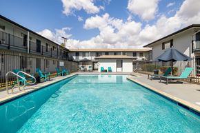El Cajon apartment for rent - A large swimming pool in front of a building with lounge chairs and umbrellas.