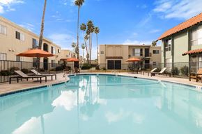 El Cajon apartment for rent - A swimming pool surrounded by palm trees and buildings.
