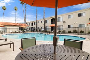 El Cajon apartment for rent - A pool area with a table and chairs under an umbrella.