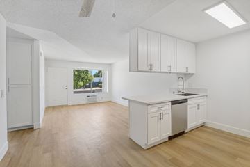 Ramona apartment for rent - A kitchen with white cabinets and a window overlooking a green area.