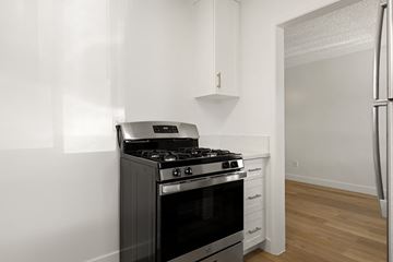 El Cajon apartment for rent - A black stove in a kitchen with white cabinets.