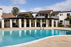 El Cajon apartment for rent - A swimming pool in front of a house with a white fence.