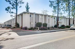 Ramona apartment for rent - A street view of a residential area with apartment buildings and parked cars.