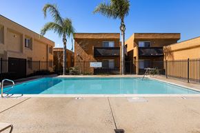 Ramona apartment for rent - A swimming pool in front of a building with palm trees.