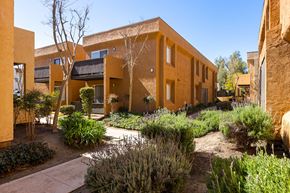 Ramona apartment for rent - A building with a yellow exterior and a garden in front.