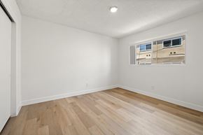 El Cajon apartment for rent - A room with wooden flooring and a window showing a building outside.