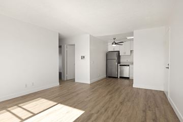 San Diego apartment for rent - A kitchen with a refrigerator, sink, and cabinets is visible through a doorway.