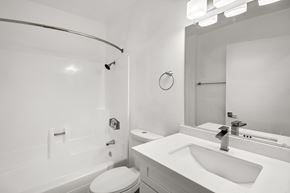 Spring Valley apartment for rent - A white bathroom with a toilet, sink, and mirror.