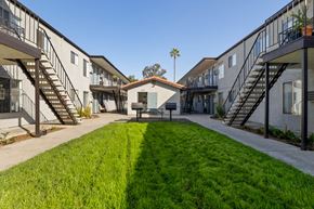 Spring Valley apartment for rent - A sunny day at a residential complex with a green lawn in the foreground.