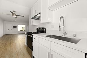 Spring Valley apartment for rent - A modern kitchen with white cabinets and a black stove top oven.