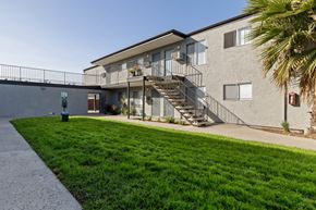 Spring Valley apartment for rent - A building with a staircase and a green lawn in front.