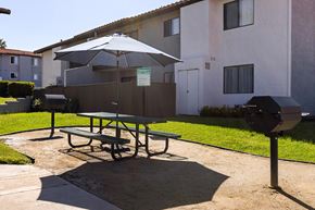 Escondido apartment for rent - A picnic table with an umbrella is in front of a building.