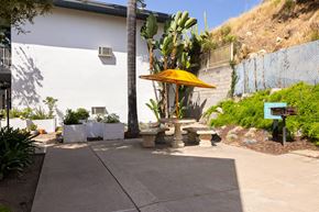 La Mesa apartment for rent - A patio area with a yellow umbrella and a white building in the background.