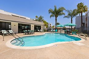 Escondido apartment for rent - A swimming pool surrounded by chairs and umbrellas.