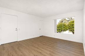 San Diego apartment for rent - A room with a white door and a window with a view of trees outside.