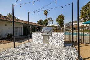 Spring Valley apartment for rent - A black and white tiled outdoor kitchen area with a grill and a pool in the background.