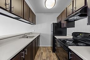Renton apartment for rent - A kitchen with dark wood cabinets and black appliances.
