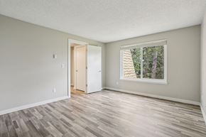 Federal Way apartment for rent - A room with a wooden floor and a window showing trees outside.