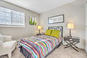Renton apartment for rent - A bedroom with a colorful bedspread and a white chair.