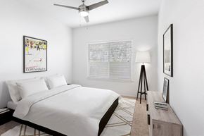 Woodland apartment for rent - A bedroom with a bed, a ceiling fan, a nightstand, a lamp, a picture frame, and a rug.